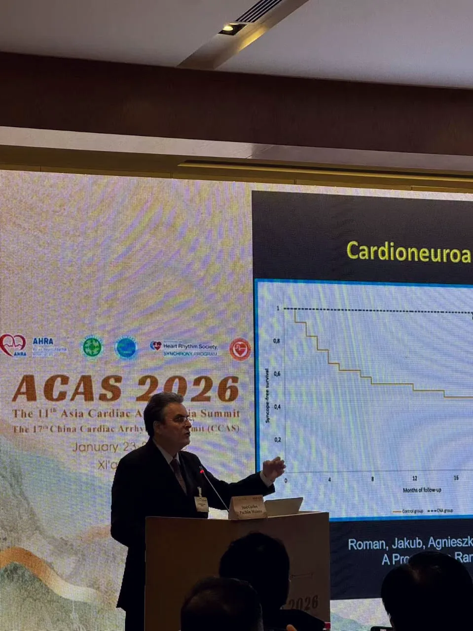 Prof. José Carlos Pachón Mateos lecturing at the podium at ACAS 2026 in Xi'an; the screen shows syncope-free survival curves comparing cardioneuroablation with the control group.